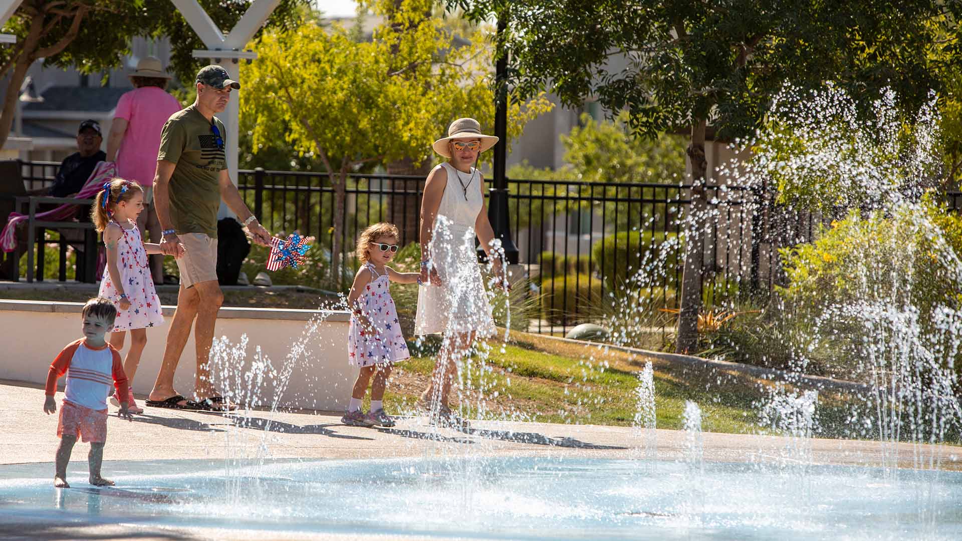 Family walking past a splash pad with the water shooting up