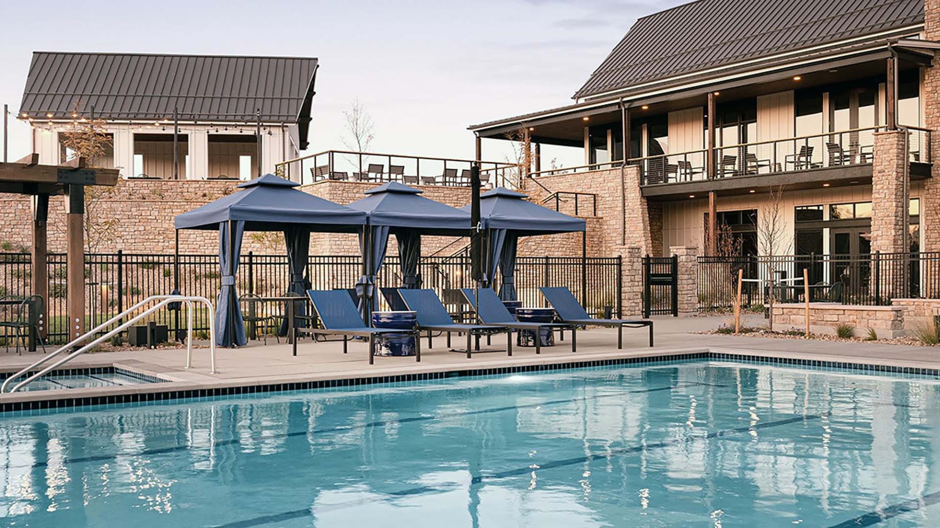 pool with chairs and cabanas, clubhouse in the background