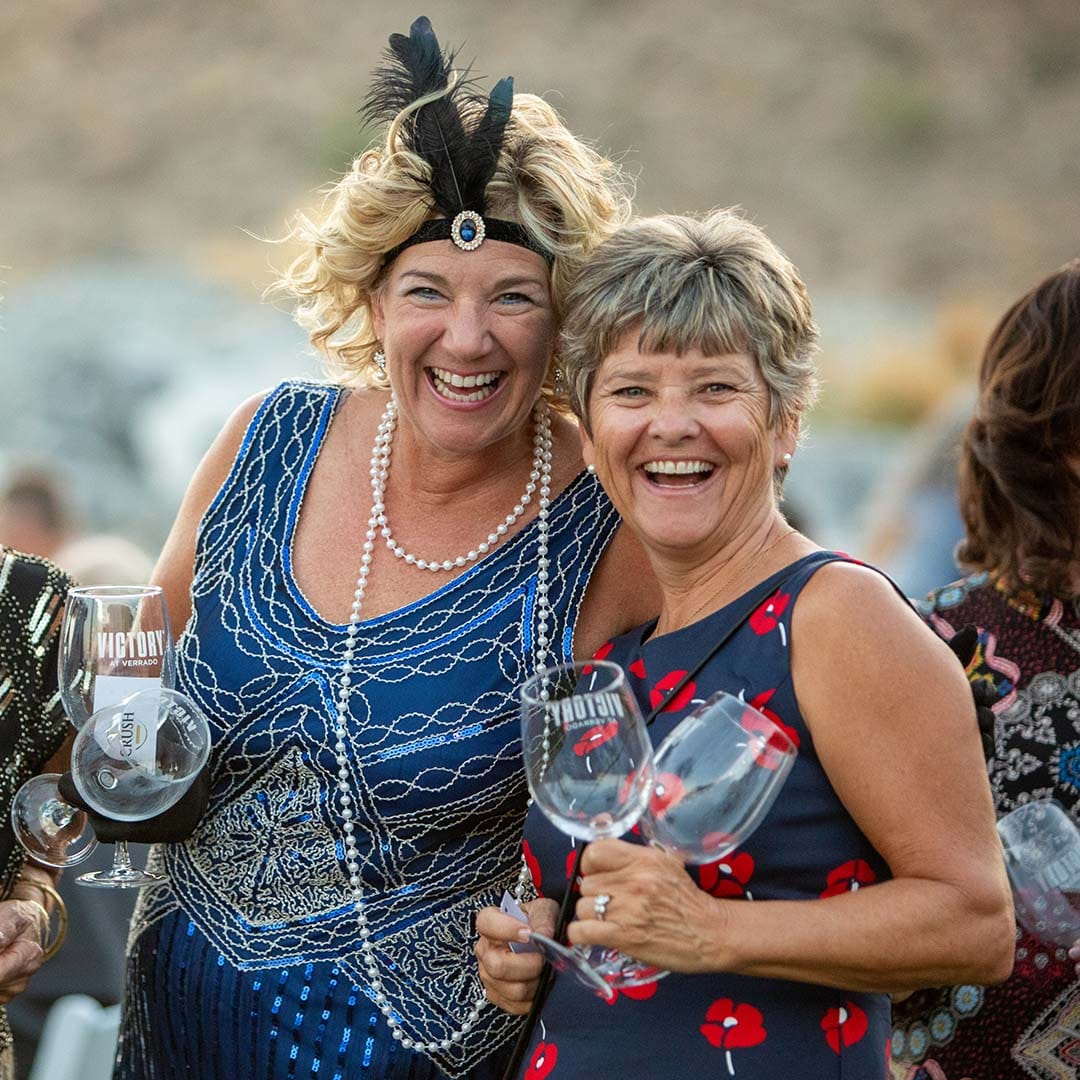 Two ladies dressed in flapper outfits smiling