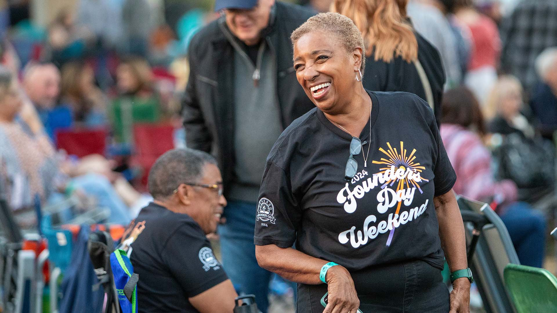 Woman smiling at Founders Day concert with neighbors in the background